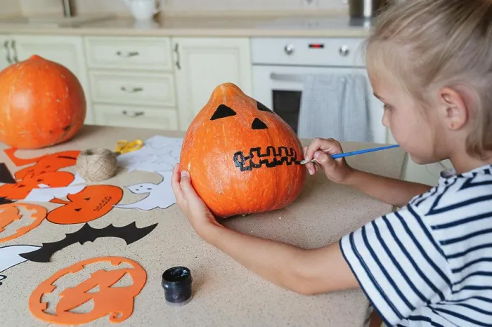 Framed Print : Girl decorating and painting pumpkin for Halloween