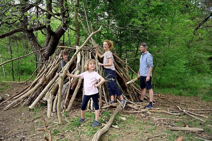 Framed Print : Girl holding log while building camp with family in forest