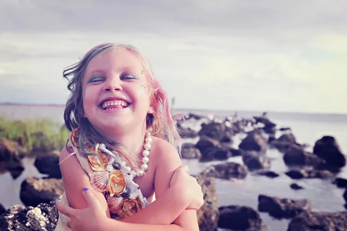 Framed Print : Girl laughing joyfully by the sea with colorful hair and pearls