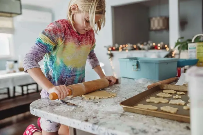 Framed Print : Girl Rolling out dough with Christmas lights in the background Framed Print : Girl Rolling out dough with Christmas lights in the background