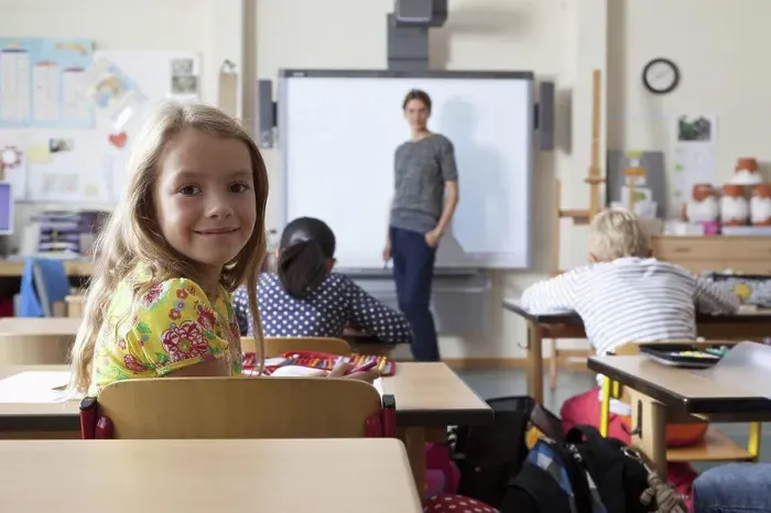 Framed Print : Girl sitting in classroom, smiling Framed Print : Girl sitting in classroom, smiling