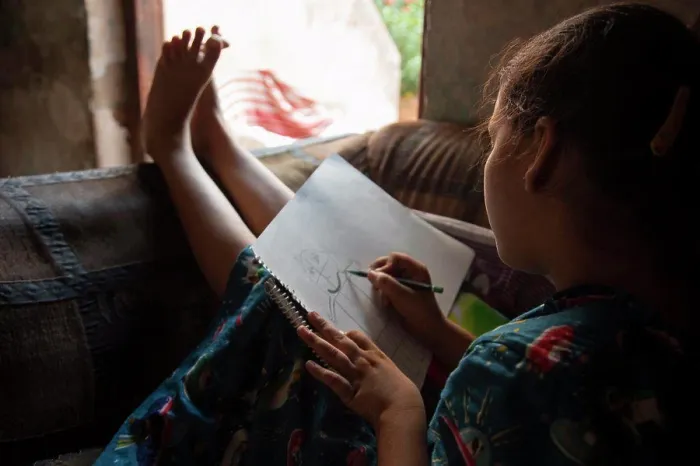 Framed Print : girl sitting on the sofa and drawing on a paper