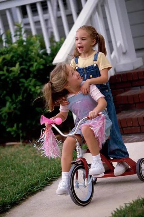 Framed Print : Two girls playing on a tricycle