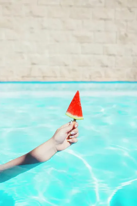 Framed Print : Hand of woman holding watermelon slice with popsicle stick in swimming pool