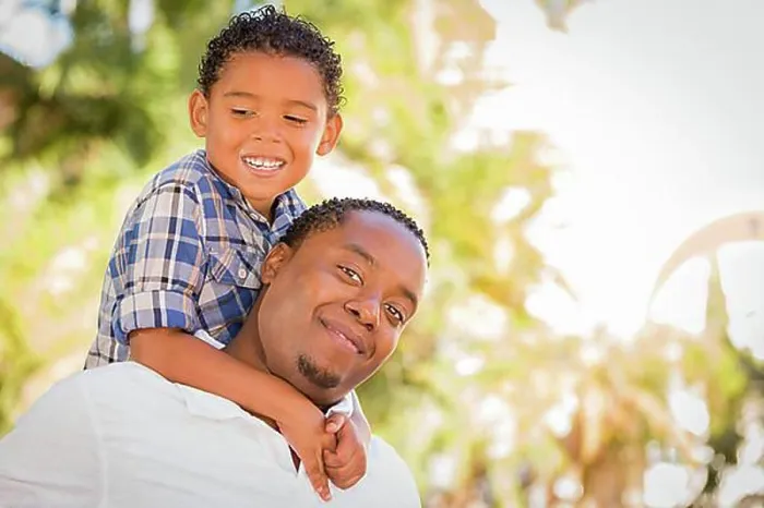 Framed Print : Happy african american father and mixed-race son playing piggyback in the park Framed Print : Happy african american father and mixed-race son playing piggyback in the park