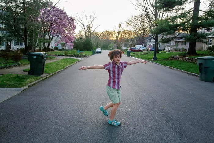 Framed Print : A happy child spins with his arms out in a street at sunset in Spring Framed Print : A happy child spins with his arms out in a street at sunset in Spring