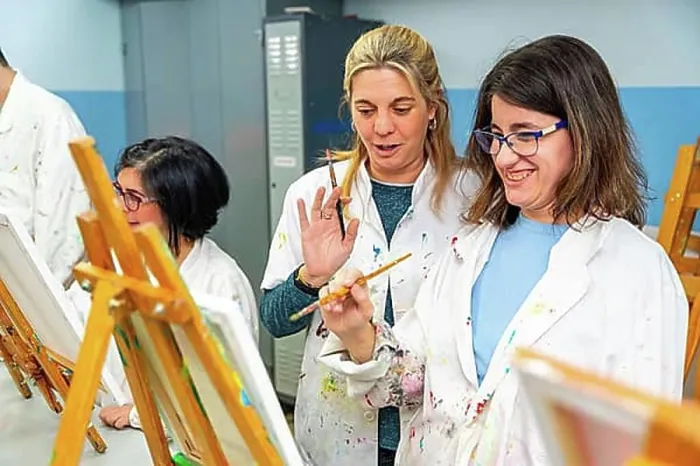 Framed Print : Happy woman with special needs painting in a canvas next to a teacher in the art class