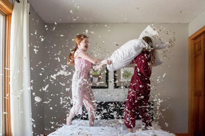 Framed Print : Two happy young girls having a feather pillow fight on the bed Framed Print : Two happy young girls having a feather pillow fight on the bed