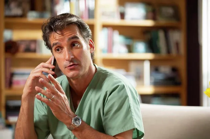 Framed Print : Hispanic Male doctor practicing tele-medicine from his home office, Talking to patient on cell phone