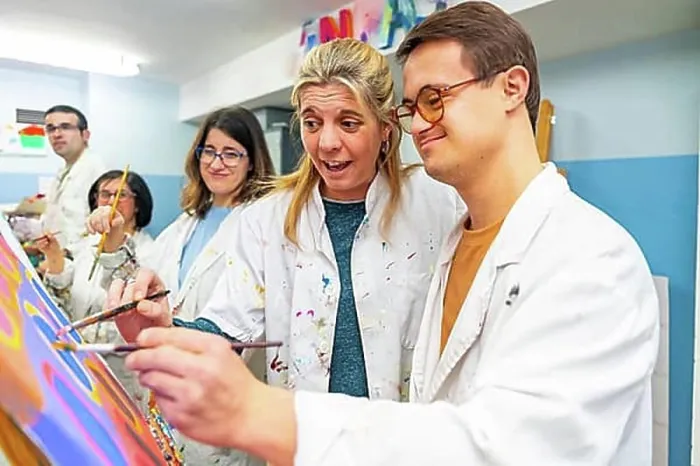 Framed Print : Instructor helping a man with down syndrome to paint on canvas in a painting class