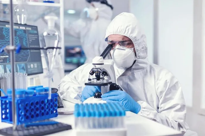 Framed Print : Lab technician in ppe gear examining virus samples under microscope Framed Print : Lab technician in ppe gear examining virus samples under microscope