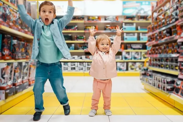 Framed Print : Little boy and girl raised their hands up at the shelf in kids store Framed Print : Little boy and girl raised their hands up at the shelf in kids store