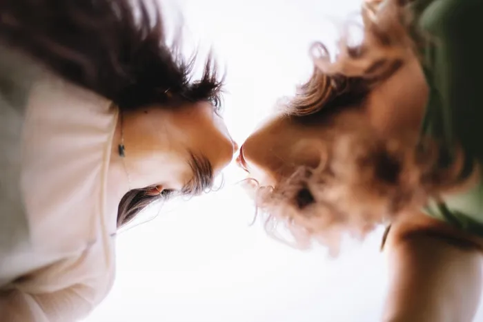 Framed Print : Low angle view of lesbian couple standing face to face about to kiss Framed Print : Low angle view of lesbian couple standing face to face about to kiss