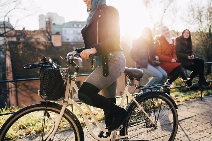 Framed Print : Low section of woman cycling by female friends sitting on railing in city