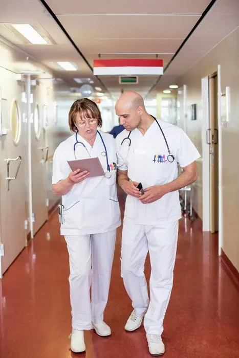 Framed Print : Male and female doctors using digital tablet while walking in hospital corridor