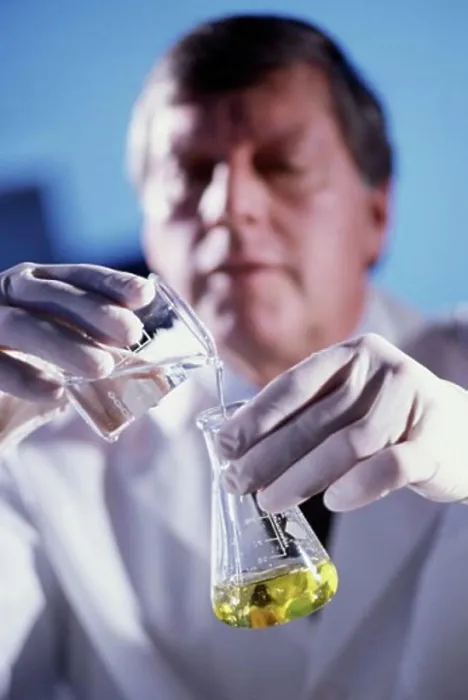Framed Print : Male researcher pouring liquid from a measuring beaker into a conical flask Framed Print : Male researcher pouring liquid from a measuring beaker into a conical flask