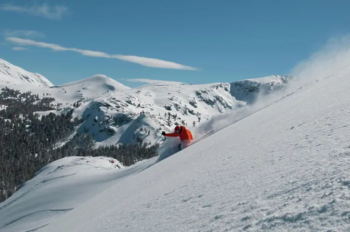 Framed Print : A male skier wearing a bright orange jacket makes a series of powder turns on a powder day at a Mountain Resort
