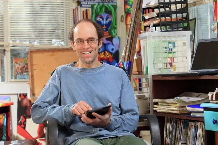 Framed Print : Man with Asperger's working on his tablet in his art studio Framed Print : Man with Asperger's working on his tablet in his art studio