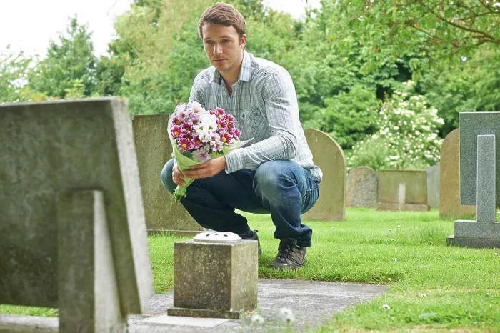 Framed Print : Man Placing Flowers By Headstone In Cemetery Framed Print : Man Placing Flowers By Headstone In Cemetery
