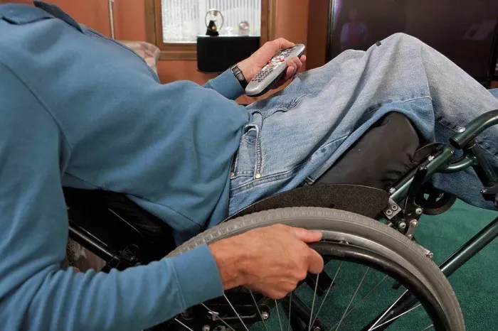 Framed Print : Man with spinal cord injury in a wheelchair using a remote control