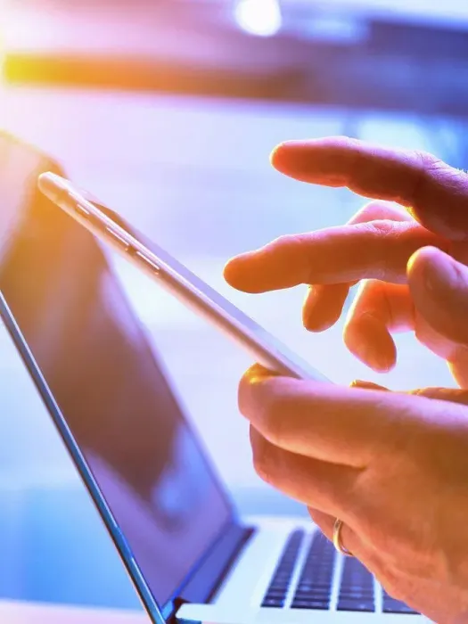 Framed Print : Man using a mobile phone with a laptop in the background Framed Print : Man using a mobile phone with a laptop in the background