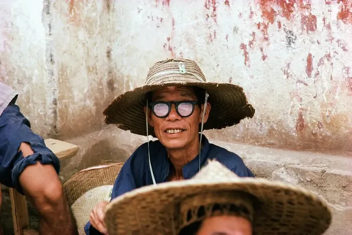 Framed Print : Man wearing a straw hat and black rimmed glasses sitting outside a building Framed Print : Man wearing a straw hat and black rimmed glasses sitting outside a building