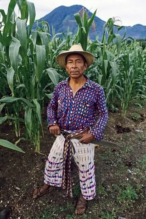 Framed Print : Mayan corn farmer wearing traditional hand woven clothing pauses under the San Pedro volcano near Lake Atitlan