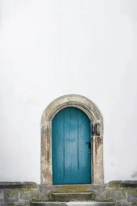 Framed Print : Medieval arched door. Aged wooden door in blue color with stone stairs and white wall Framed Print : Medieval arched door. Aged wooden door in blue color with stone stairs and white wall
