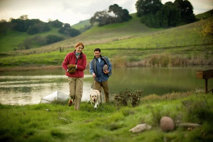 Framed Print : Mid-adult couple with their dog are carrying rocks beside a pond Framed Print : Mid-adult couple with their dog are carrying rocks beside a pond