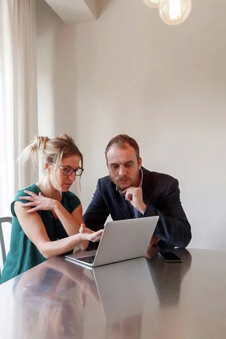Framed Print : Mid adult couple sitting at table, looking at laptop Framed Print : Mid adult couple sitting at table, looking at laptop