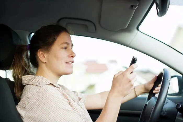 Framed Print : Mid adult woman dialing on mobile phone while driving Framed Print : Mid adult woman dialing on mobile phone while driving
