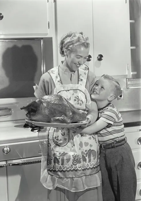 Framed Print : Mid adult woman holding a roast turkey with her son hugging her Framed Print : Mid adult woman holding a roast turkey with her son hugging her