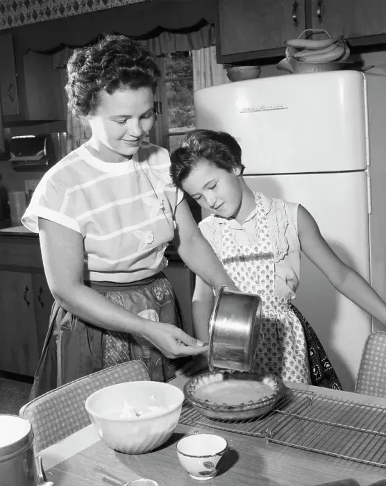 Framed Print : Mid adult woman preparing food with her daughter standing beside her Framed Print : Mid adult woman preparing food with her daughter standing beside her