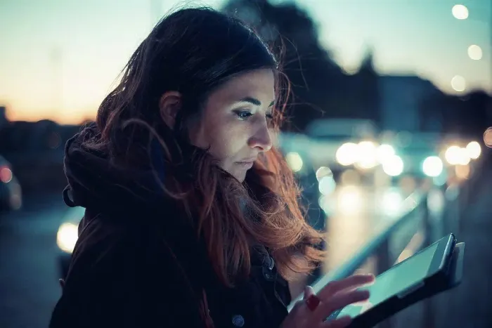 Framed Print : Mid adult woman using digital tablet touchscreen on street at dusk Framed Print : Mid adult woman using digital tablet touchscreen on street at dusk