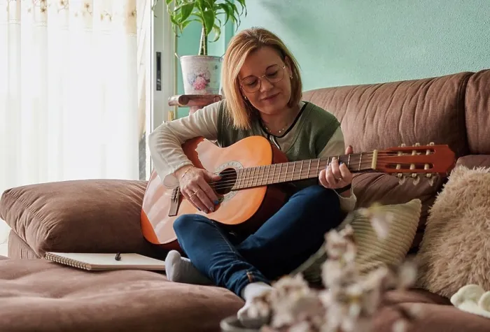 Framed Print : Middle-aged woman plays guitar on the sofa in the living room at home Framed Print : Middle-aged woman plays guitar on the sofa in the living room at home