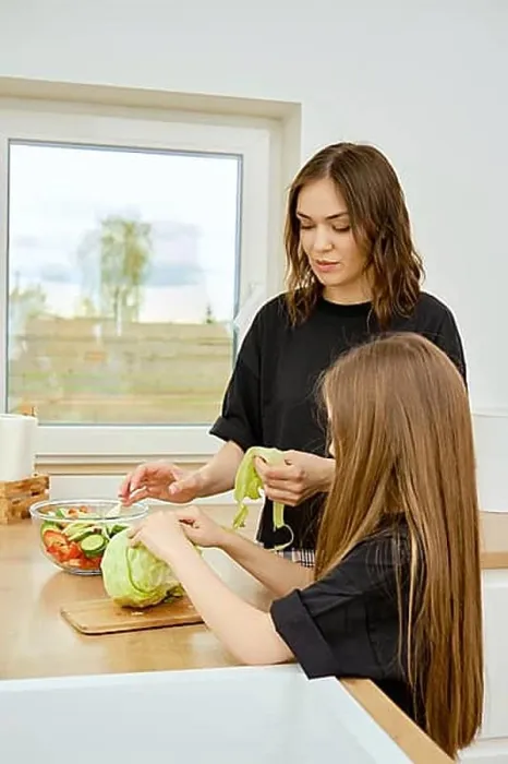 Framed Print : Mother and daughter tearing iceberg lettuce leaves into pieces while making food at home Framed Print : Mother and daughter tearing iceberg lettuce leaves into pieces while making food at home