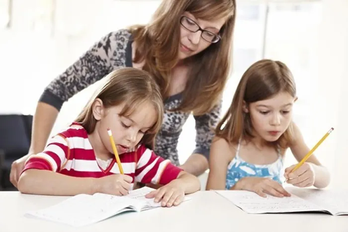 Framed Print : Mother helping two daughters with homework