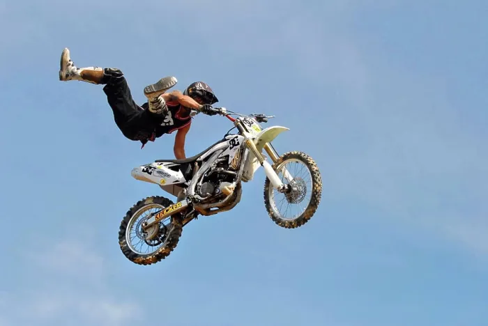 Framed Print : A motocross rider performing a stunt while flying through the air on his motorcycle in a blue sky background Framed Print : A motocross rider performing a stunt while flying through the air on his motorcycle in a blue sky background