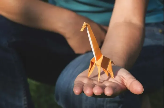 Framed Print : Origami orange color giraffe on hand