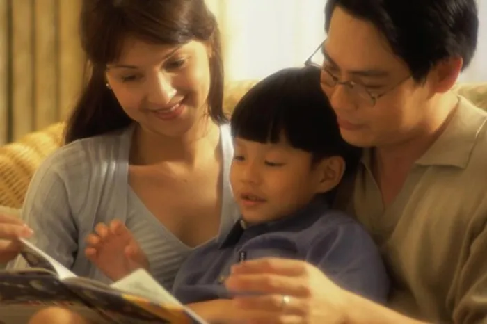 Framed Print : Parents with their son reading a book