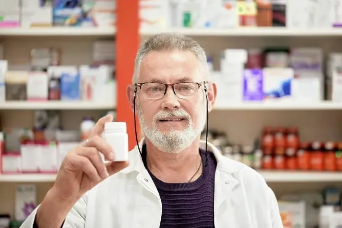 Framed Print : Pharmacist wearing eyeglasses holding bottle of medicine at pharmacy store Framed Print : Pharmacist wearing eyeglasses holding bottle of medicine at pharmacy store