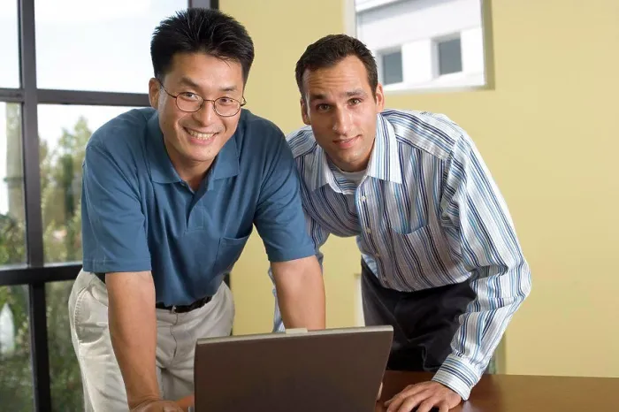 Framed Print : Portrait of two businessmen standing in front of a laptop Framed Print : Portrait of two businessmen standing in front of a laptop