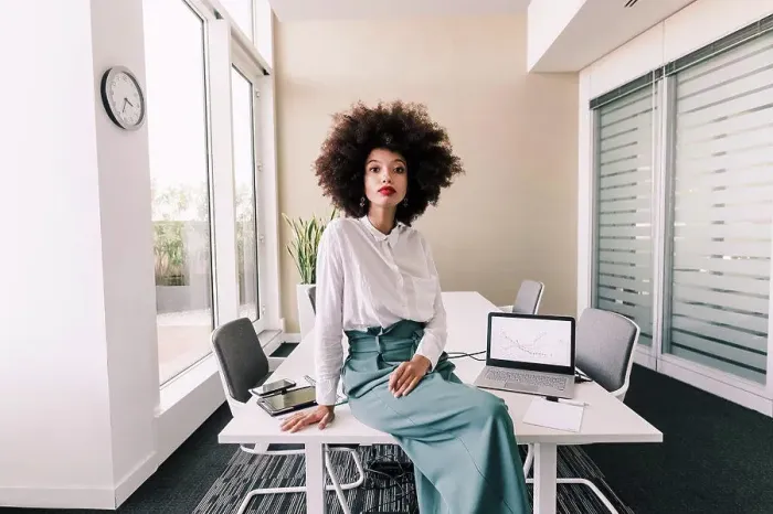 Framed Print : Portrait of businesswoman sitting on desk in office Framed Print : Portrait of businesswoman sitting on desk in office