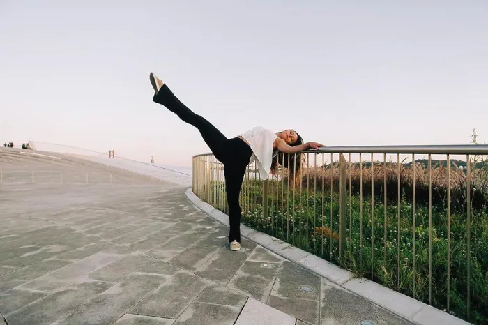 Framed Print : Portrait carefree young female dancer doing standing splits at park railing Framed Print : Portrait carefree young female dancer doing standing splits at park railing