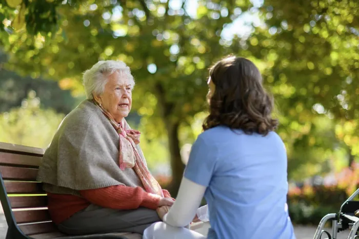 Framed Print : Portrait of nurse and elderly woman sitting on bench in park during warm autumn day Framed Print : Portrait of nurse and elderly woman sitting on bench in park during warm autumn day