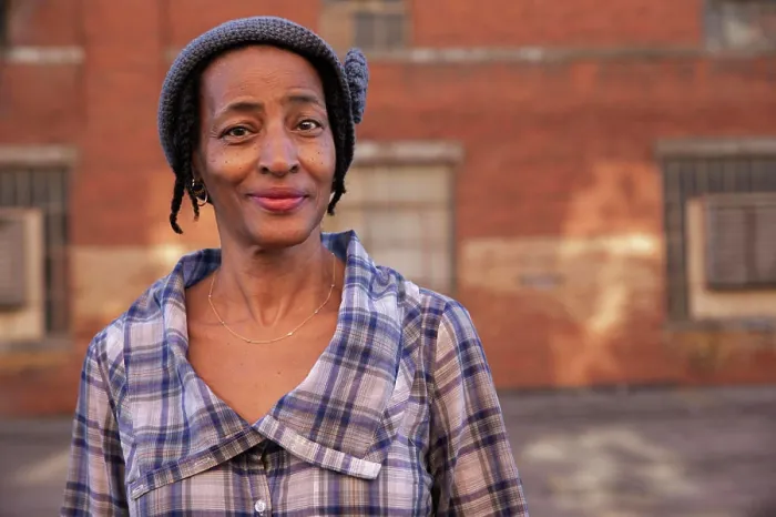 Framed Print : Portrait of older woman wearing knit hat standing in alley smiling looking at camera, brick wall in background Framed Print : Portrait of older woman wearing knit hat standing in alley smiling looking at camera, brick wall in background