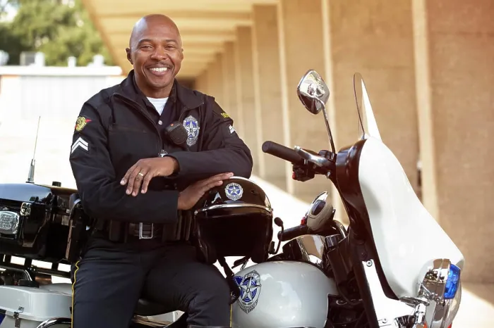 Framed Print : Portrait of Police officer sitting on his motorcycle outside looking towards camera smiling