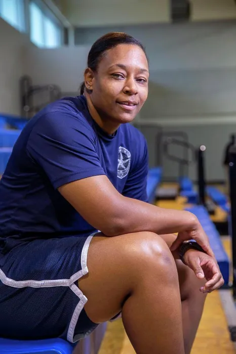 Framed Print : Portrait of Police woman sitting on bleachers in gymnasium looking towards camera smiling