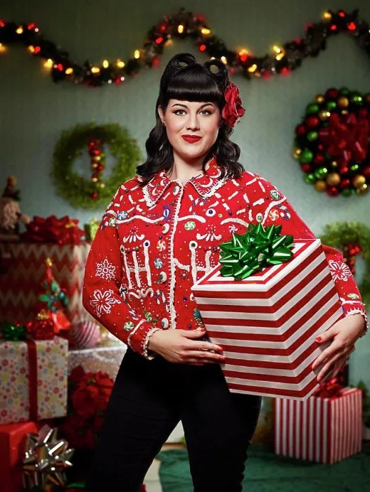 Framed Print : Portrait of woman with a retro hair style, in an 'ugly' Christmas sweater holding a present looking at the camera Framed Print : Portrait of woman with a retro hair style, in an 'ugly' Christmas sweater holding a present looking at the camera