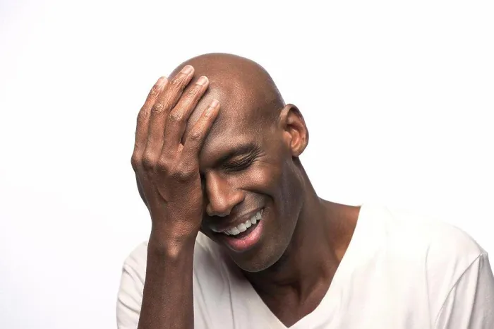 Framed Print : Portrait of young bald African American man with hand on his head looking down with eyes closed
